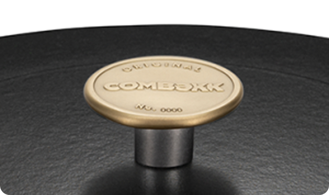 Gouden knop met het opschrift "Combekk" op een zwarte gietijzeren deksel uit de Original-collectie.